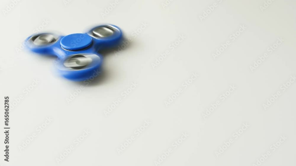 Rotating blue fidget spinner on a white background. Rotating blue fidget spinner on a white background.