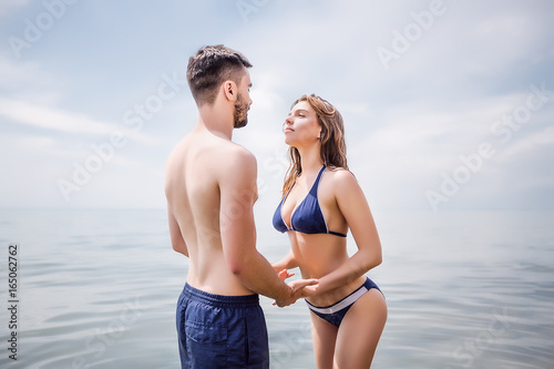 Sexy couple at sea,slim body,long hair,swimwear,swimsuit,beautiful tan,summer holidays concept,make up,bearded man