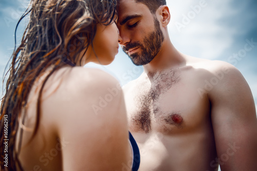 Sexy couple at sea,slim body,long hair,swimwear,swimsuit,beautiful tan,summer holidays concept,make up,bearded man