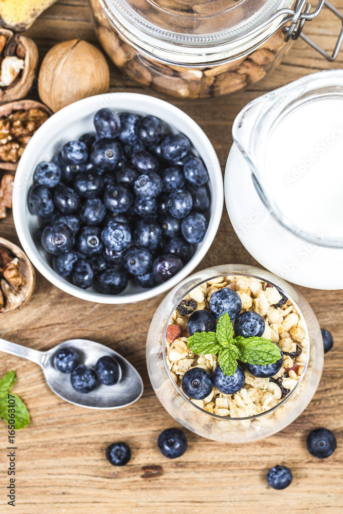 Healthy breakfast: oat granola with yogurt and fresh blueberries on wooden background