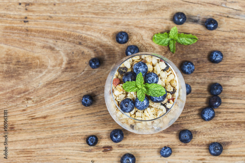 Healthy breakfast: oat granola with yogurt and fresh blueberries on wooden background