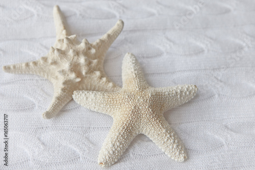 Decorative white starfish on a background of knitted fabrics. Selective focus.