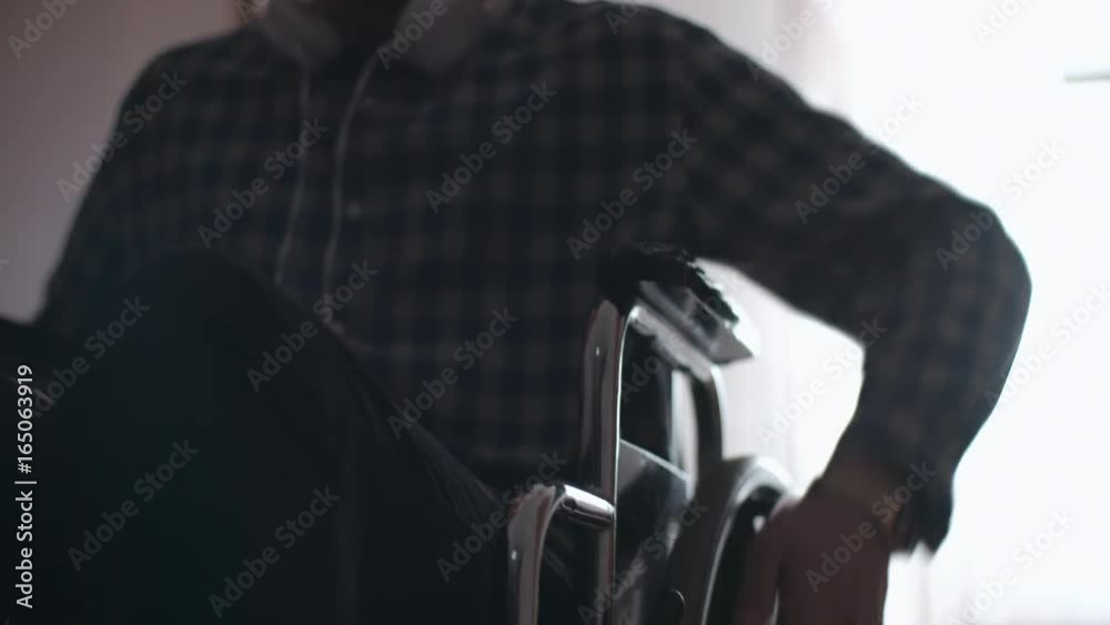 Dolly with tilt up of unrecognizable young man turning wheels of