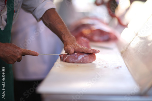 Butcher on the agricultural market prepares for sale beef fillet