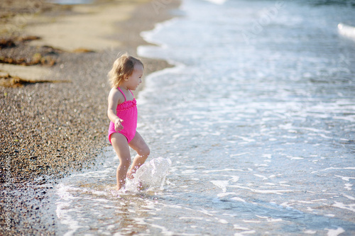 The cute little girl runs on the beach at the seashore