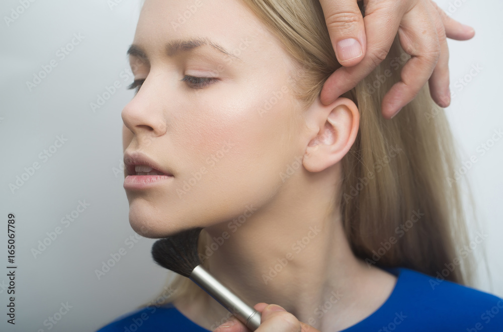 Woman getting powder on face with makeup brush Woman getting powder on face with makeup brush