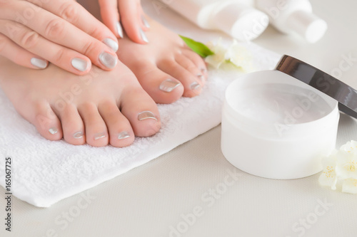 Young woman s feet with moisturizing cream. Smooth skin. Spring and summer atmosphere with fresh and fragrant white jasmine.