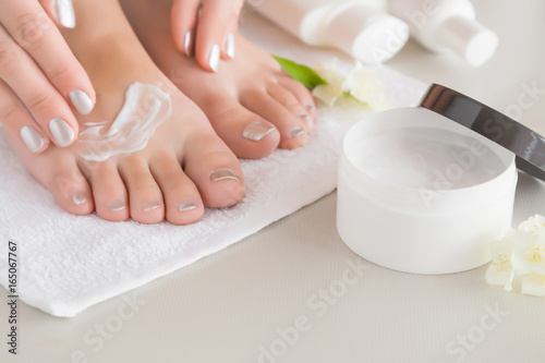 Young woman's feet with moisturizing cream. Smooth skin. Spring and summer atmosphere with fresh and fragrant white jasmine.