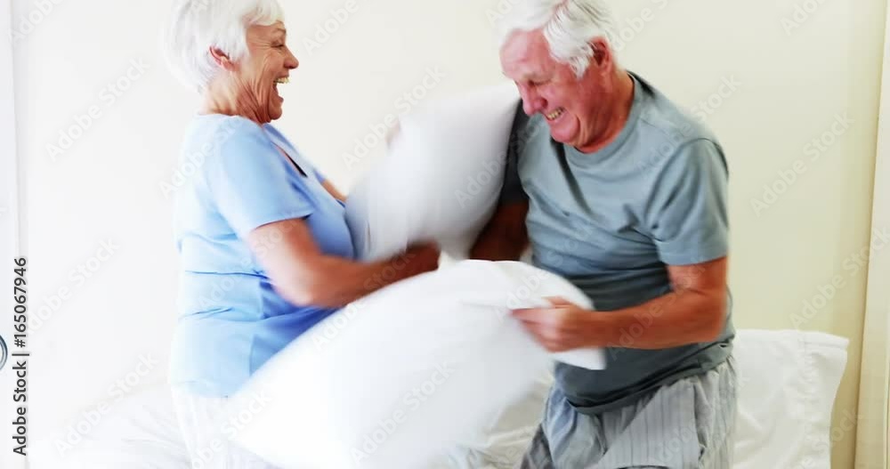 Smiling couple having pillow fight on bed Smiling couple having pillow fight on bed