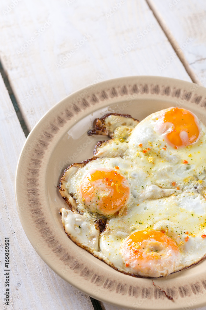 Homemade fried eggs on the plate above wooden table