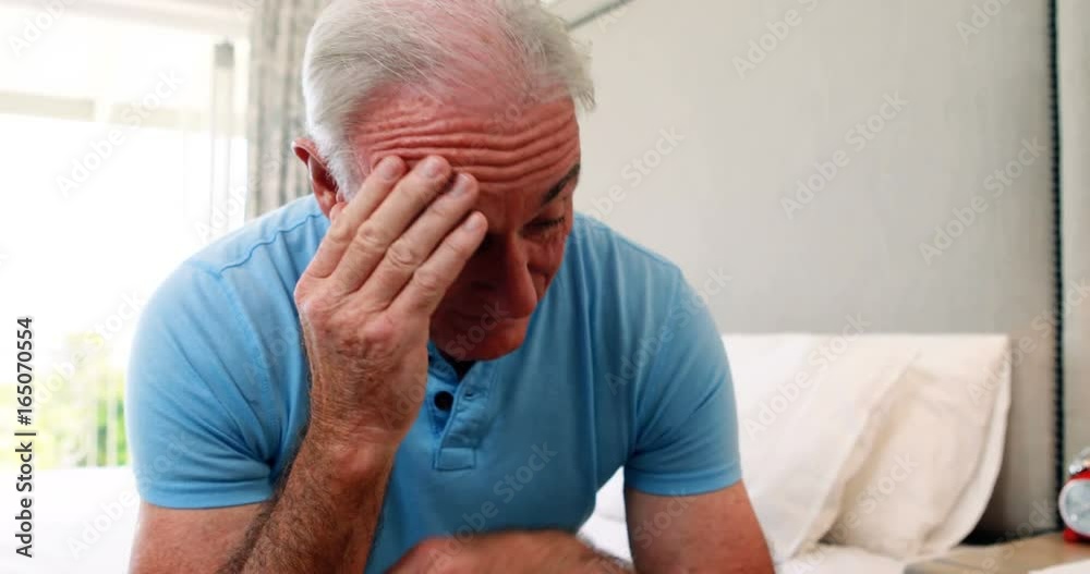 Tense senior man sitting on bed in bedroom Tense senior man sitting on bed in bedroom