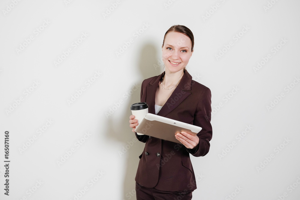 Smiling businesswoman working on digital tablet in a bright office isolated on a white background. Looking directly at the camera. Girl in elegant office suit. Smiling businesswoman working on digital tablet in a bright office isolated on a white background. Looking directly at the camera. Girl in elegant office suit.