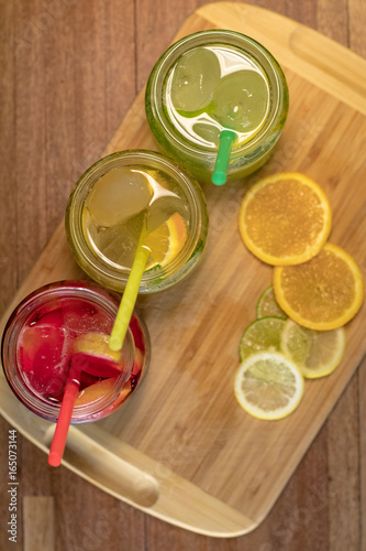 Three glasses of different flavored lemonades on the counter served in jars