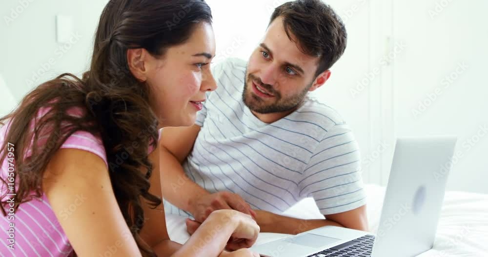 Couple interacting with each other while using laptop on bed Couple interacting with each other while using laptop on bed