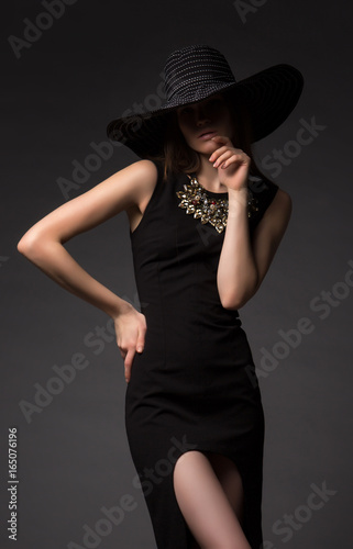 Portrait of a beautiful girl  model in a beautiful evening dress  decoration and hat. Fashion  style  beauty  lifestyle  studio.