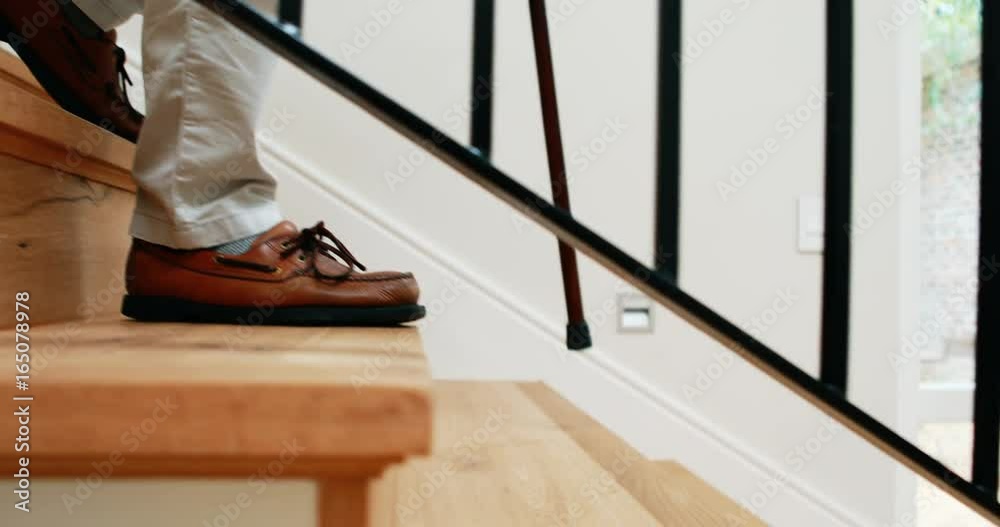Senior man climbing downstairs with walking stick