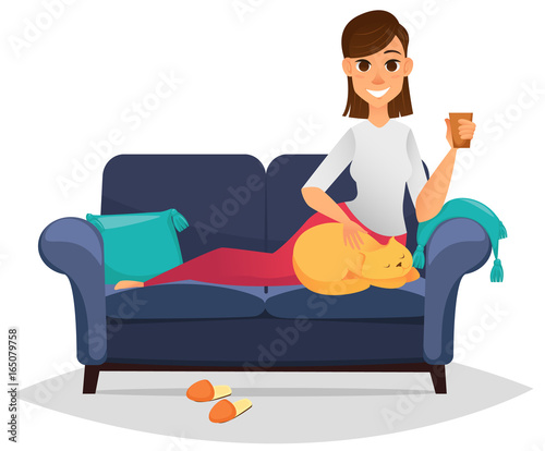 Woman on a comfortable sofa holding cup and stroking her cat