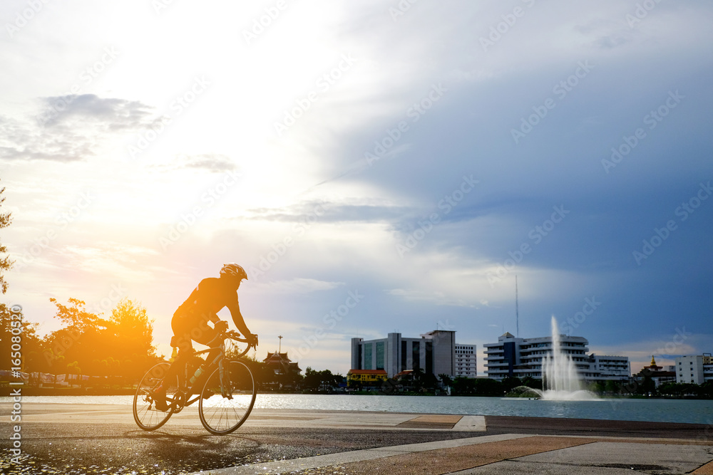 Fototapeta premium Cyclist in motion on background beautiful sunset with silhouette. Ride on bike on the road . Man ride bicycle in the road.silhouette of cyclist in summer concept. Cyclist in city park.