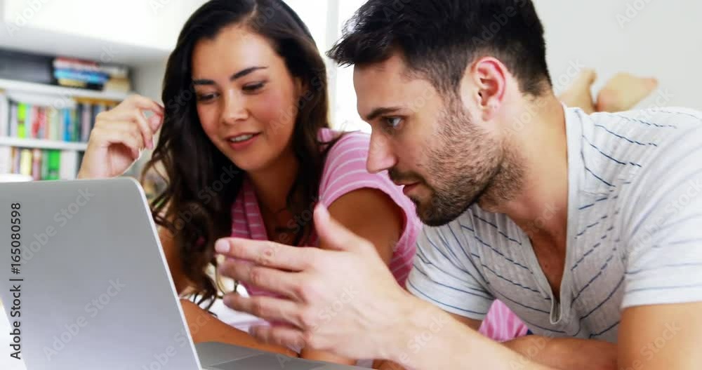 Couple interacting with each other while using laptop on bed Couple interacting with each other while using laptop on bed