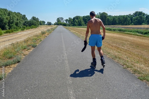 Canvas Print A man in shorts rides on roller skates along the path along the Danube River
