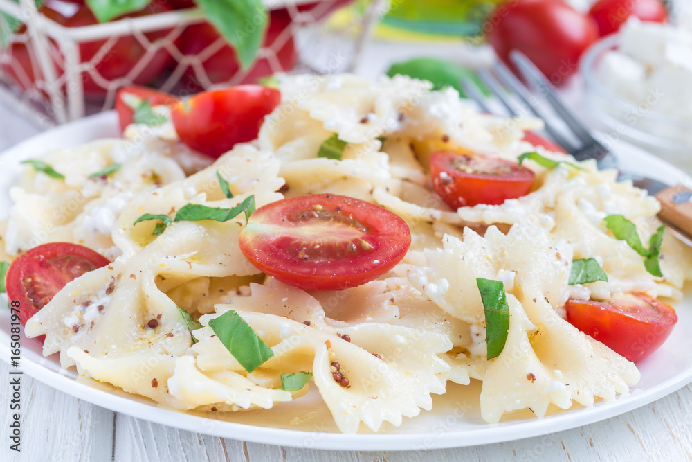 Pasta salad with tie pasta, feta cheese, tomatoes, mustard and basil, horizontal Pasta salad with tie pasta, feta cheese, tomatoes, mustard and basil, horizontal