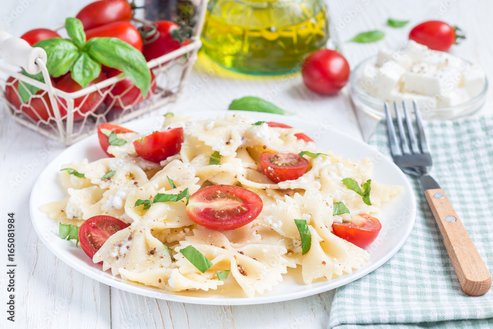 Pasta salad with tie pasta, feta cheese, tomatoes, mustard and basil, horizontal Pasta salad with tie pasta, feta cheese, tomatoes, mustard and basil, horizontal