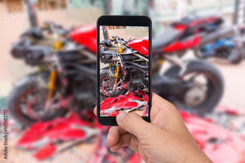 Close up hand  holding smartphone and take photo of motorbike accident