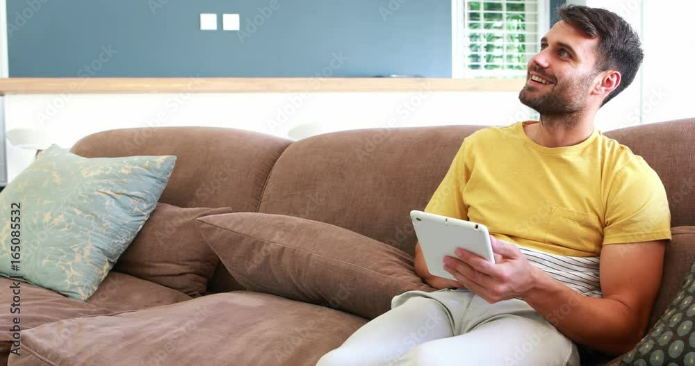 Smiling couple using digital tablet on sofa in the living room Smiling couple using digital tablet on sofa in the living room
