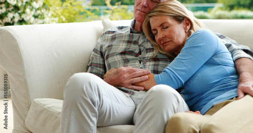 Senior couple relaxing on sofa in living room Senior couple relaxing on sofa in living room