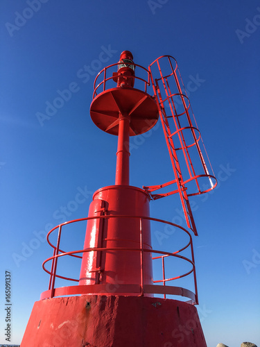 Red Lighthouse inside at port with blue sky photo
