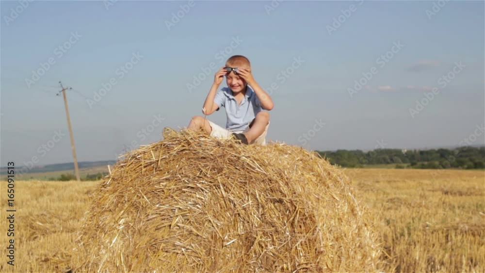 child is sitting on a straw/Funny Child Sitting On Haystack Playing With Straw child is sitting on a straw/Funny Child Sitting On Haystack Playing With Straw