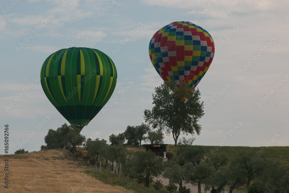 Naklejka premium Due mongolfiere in volo sopra ad un paesaggio rurale umbro