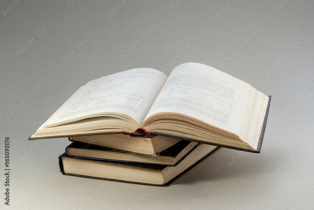 Old books with redened pages are stacked. Open book above Old books with redened pages are stacked. Open book above