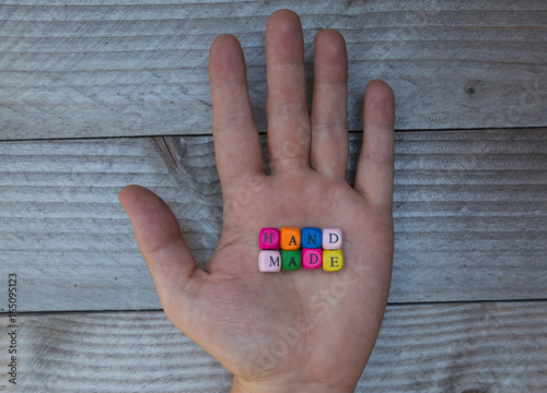 Handmade Buchstabenwürfel in Hand auf grauem Holz visualisierung photo