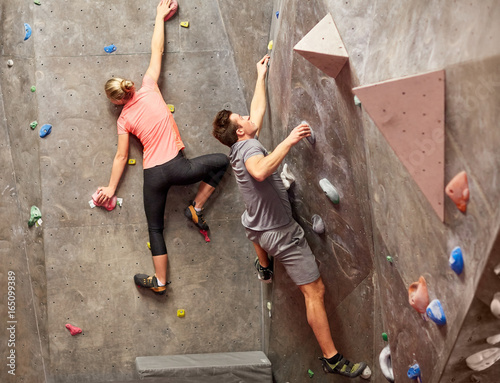 man and woman training at indoor climbing gym wall