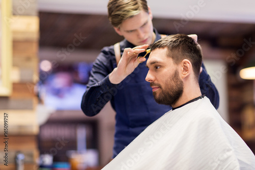 man and barber cutting hair at barbershop