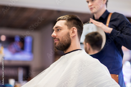 man and hairdresser with mirror at barbershop