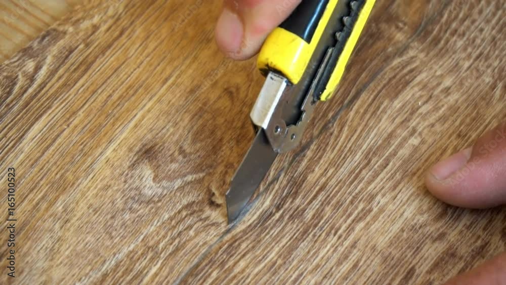 the worker cuts off the linoleum with a utility knife,fitting of