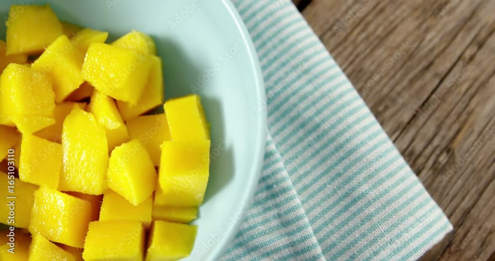 Chopped mangoes in bowl on wooden table Chopped mangoes in bowl on wooden table