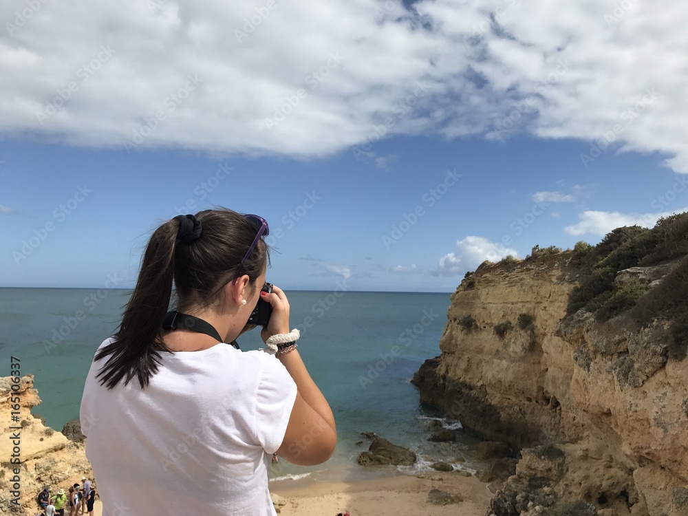 turista fotografiando los acantilados del Algarve en Portugal