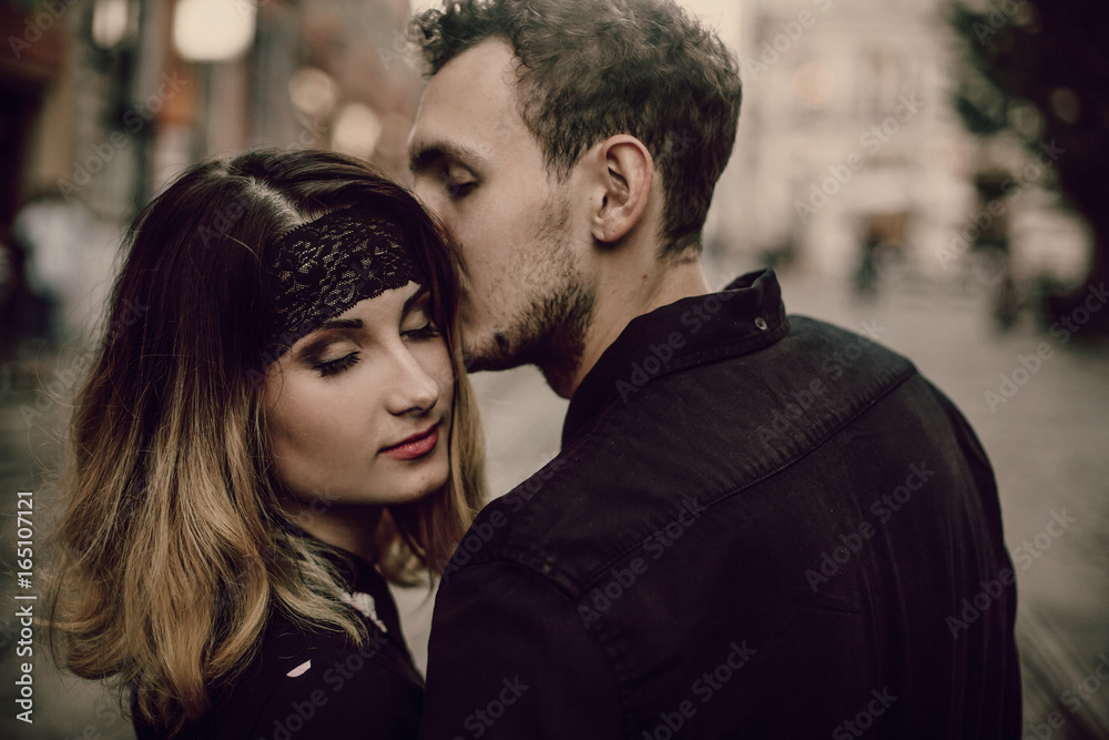 Close-up of a romantic couple kissing, handsome bearded man kissing sensual blonde woman outdoors portrait, passion concept