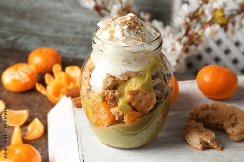 Delicious yogurt parfait with mandarin and cookies in jar on table