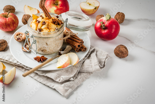 Healthy vegan food. Dietary breakfast or snack. Apple pie overnight oats, with apples, yogurt, cinnamon, spices, walnuts. In a glass, on a white marble table. Copy space