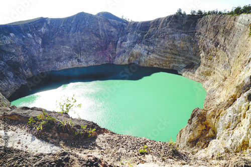 High panoramic view of the green turquoise colored lake in the Kelimutu volcano during the morning at sunrise with nobody around, Indonesia.