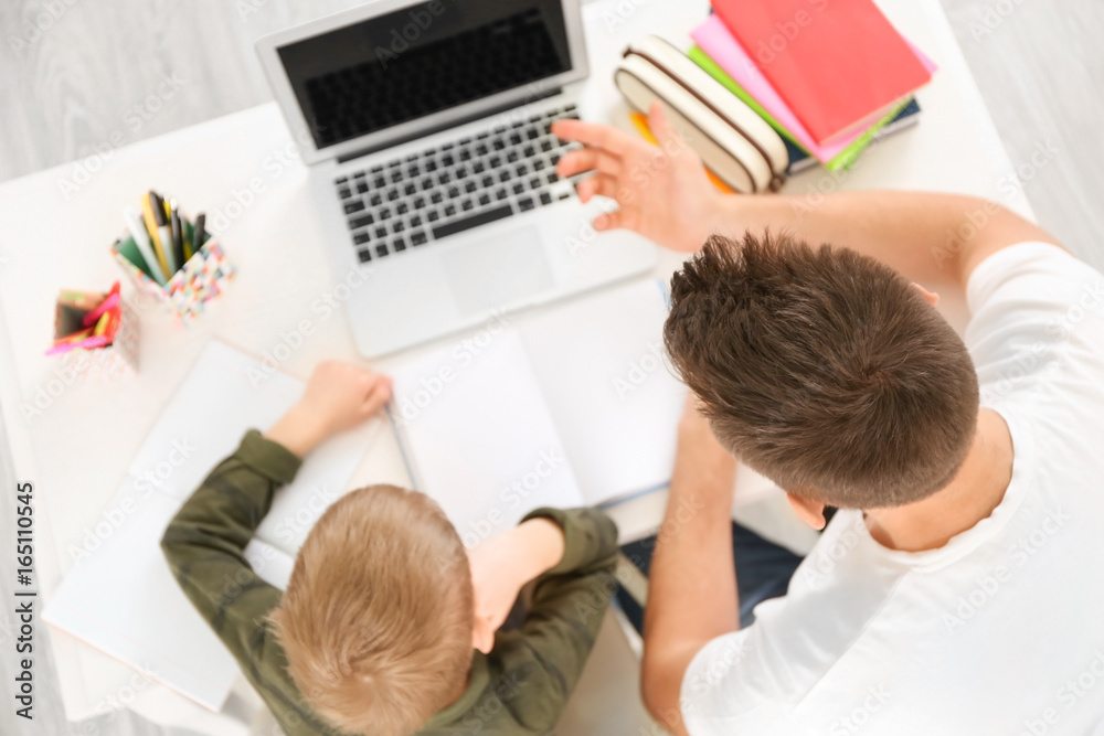 Father and son doing homework together at home - obrazy, fototapety, plakaty 