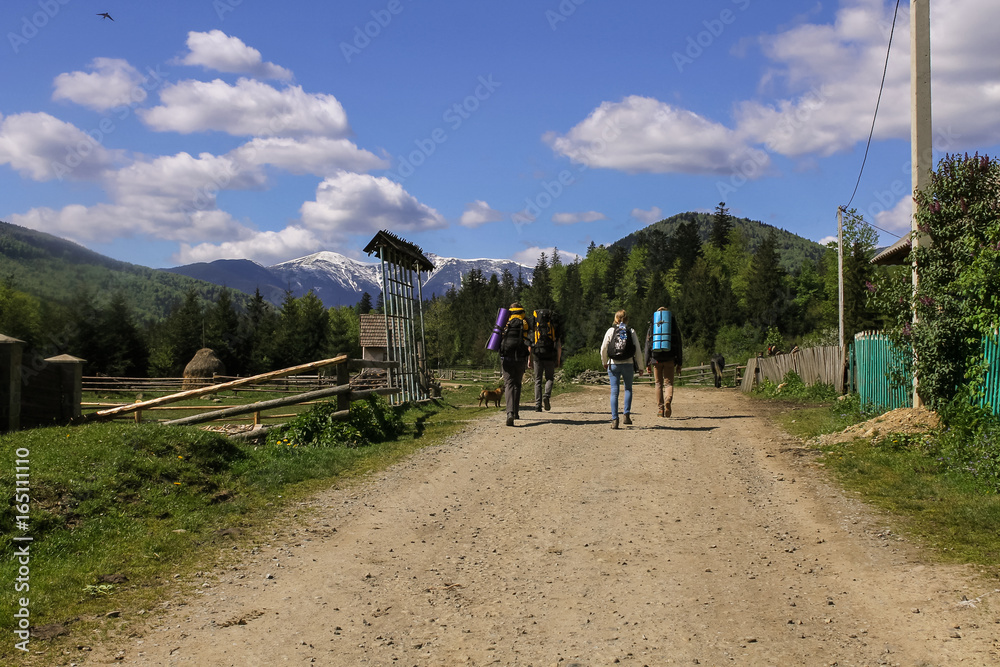 Group of hikers walking on forest road towards mountain range adventure freedom healthy activity backpacking spring