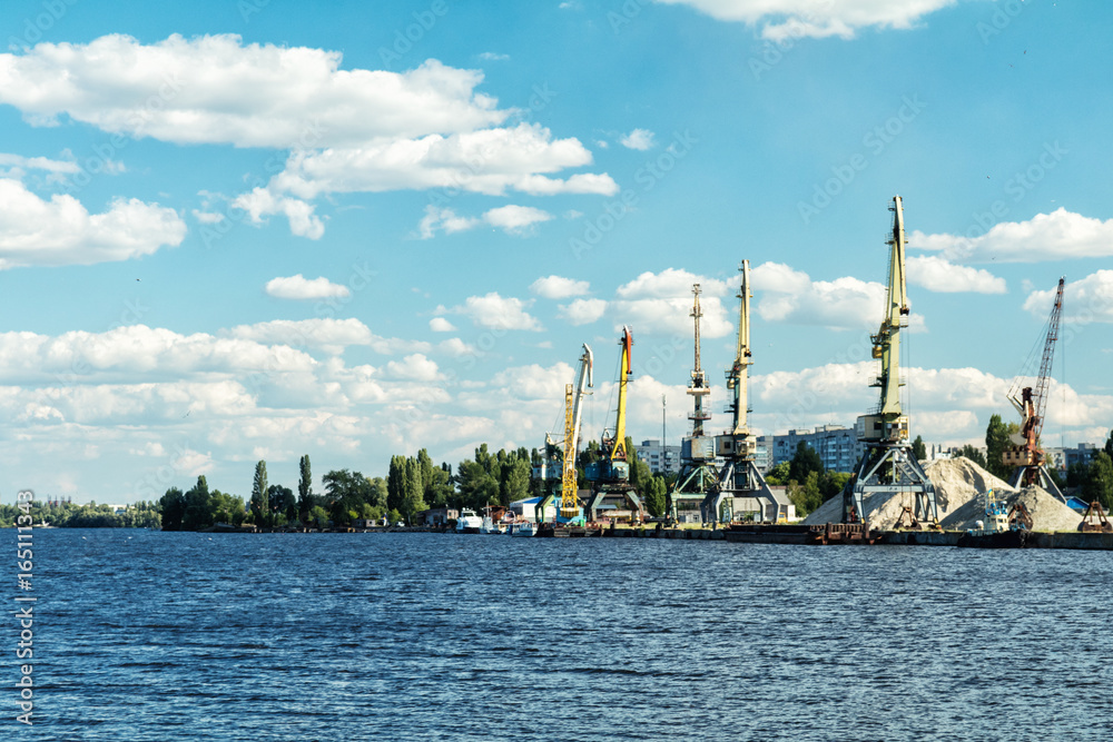 Obraz premium Container cranes in Dnieper river harbor. Loading and unloading cranes in the river port. The river port accepts and ships the cargo across the water.