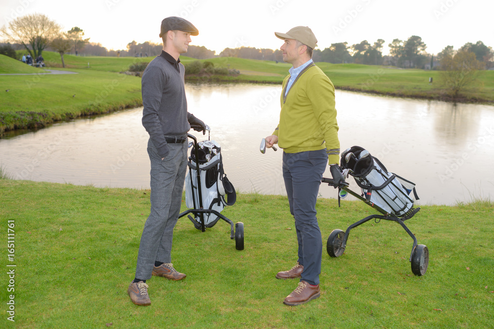 Male golfers chatting on the golf course Male golfers chatting on the golf course