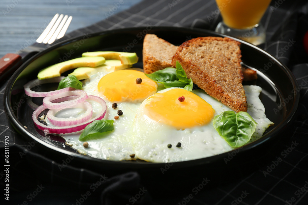 Delicious over easy eggs with toasts, onion and avocado on kitchen table Delicious over easy eggs with toasts, onion and avocado on kitchen table