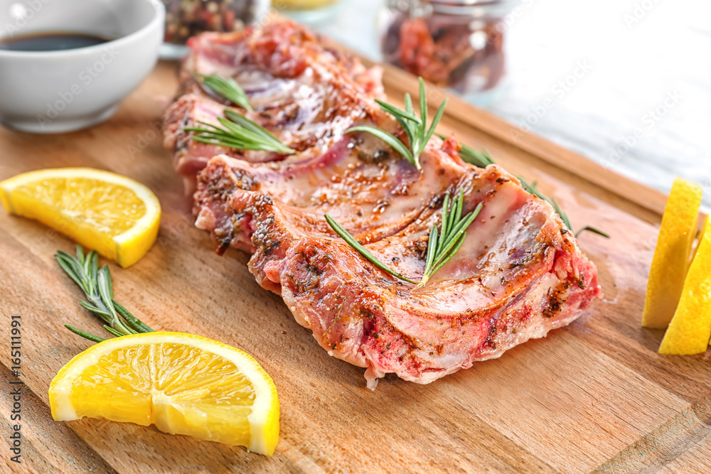 Raw pork ribs and lemon slices on wooden board, closeup Raw pork ribs and lemon slices on wooden board, closeup